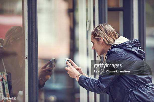 woman taking a photo with smartphone - butiksfönster bildbanksfoton och bilder