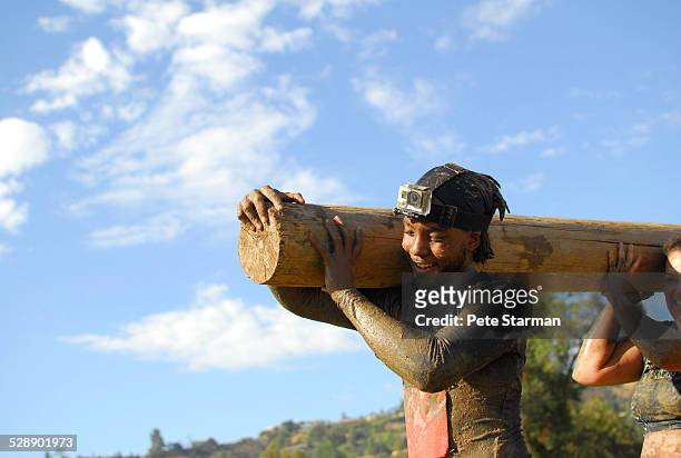 couple competing in 5k, carrying log obstacle. - assault courses stock pictures, royalty-free photos & images