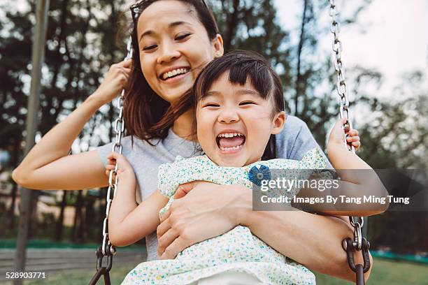 mom & toddler swinging on swing joyfully in park - sonrisa con dientes fotografías e imágenes de stock