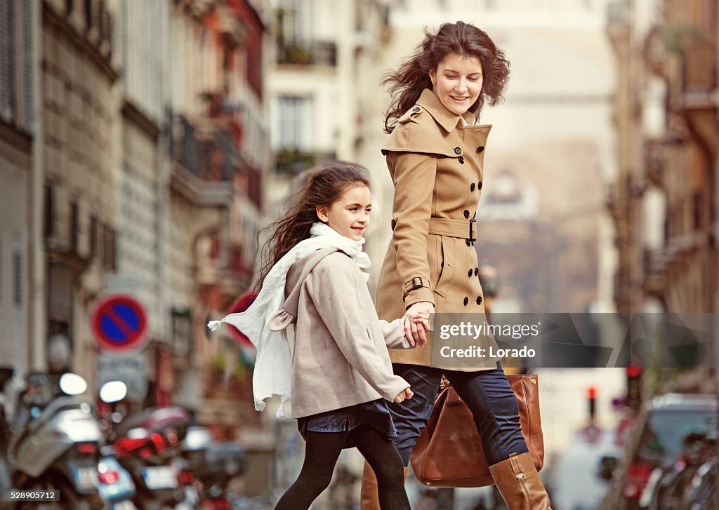 Brunette mother daughter walking in Paris streets on spring afternoon