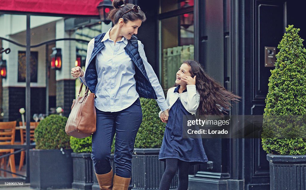 Brunette mother daughter walking in Paris streets on spring afternoon