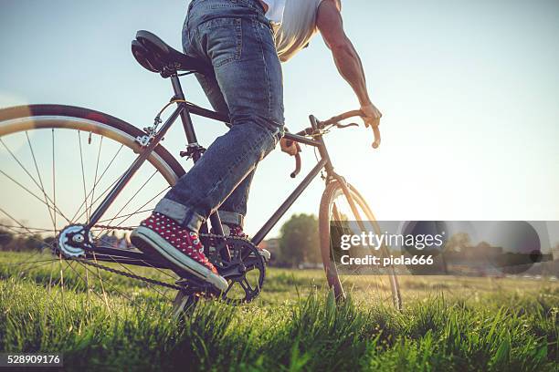 hipster mann auf seinem fahrrad auf dem rasen - fahrrad grün stock-fotos und bilder