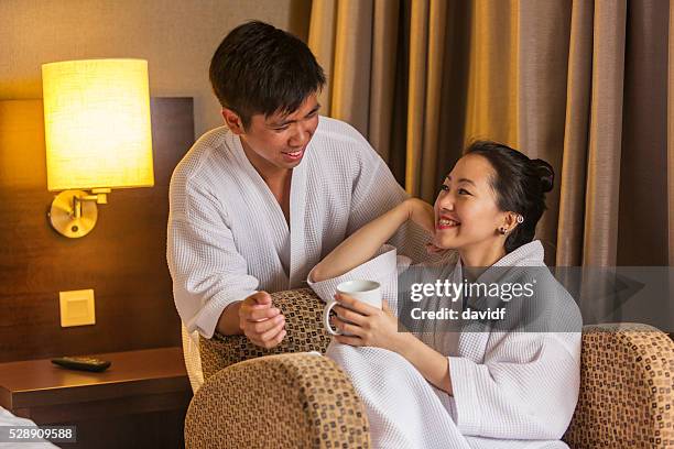 bademantel mit junge asiatische paar mit einem warmen getränk - asian couple having hi tea stock-fotos und bilder