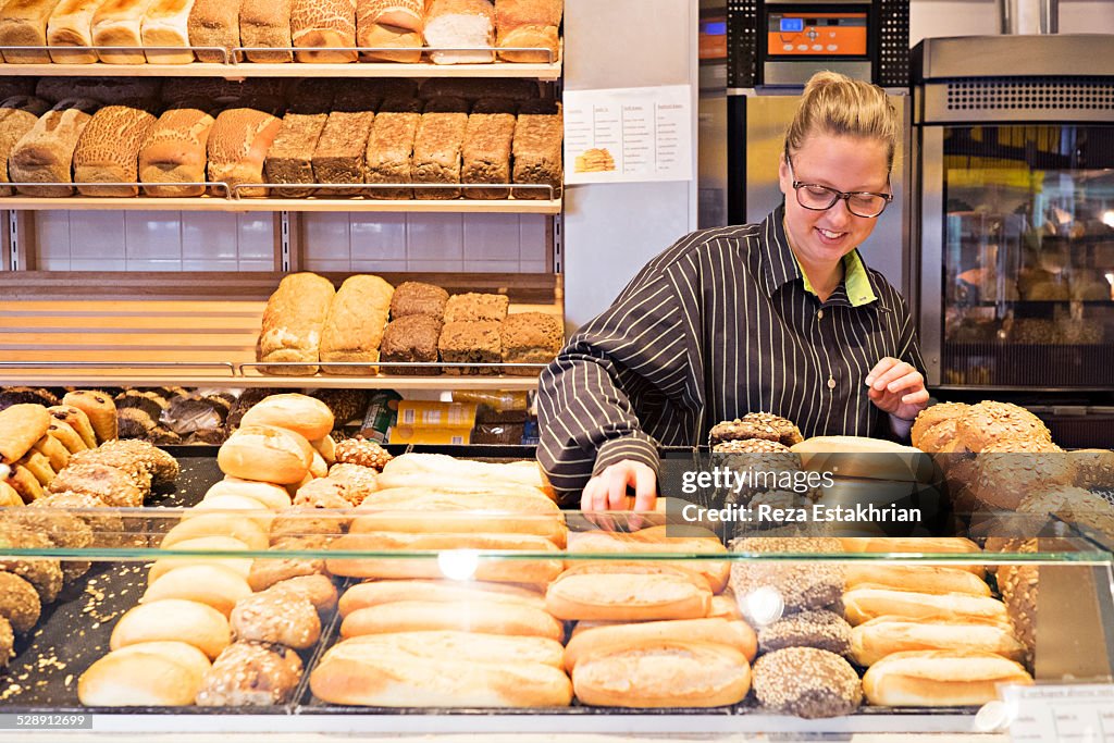 Woman arranges bread in shop