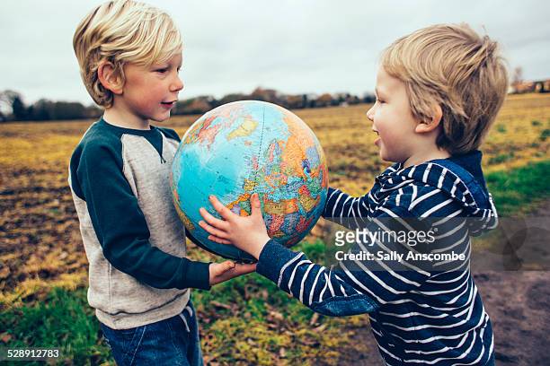 two children passing a globe to each other - day 6 stock-fotos und bilder