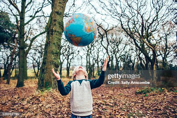 child throwing a globe up in the air - child globe stockfoto's en -beelden