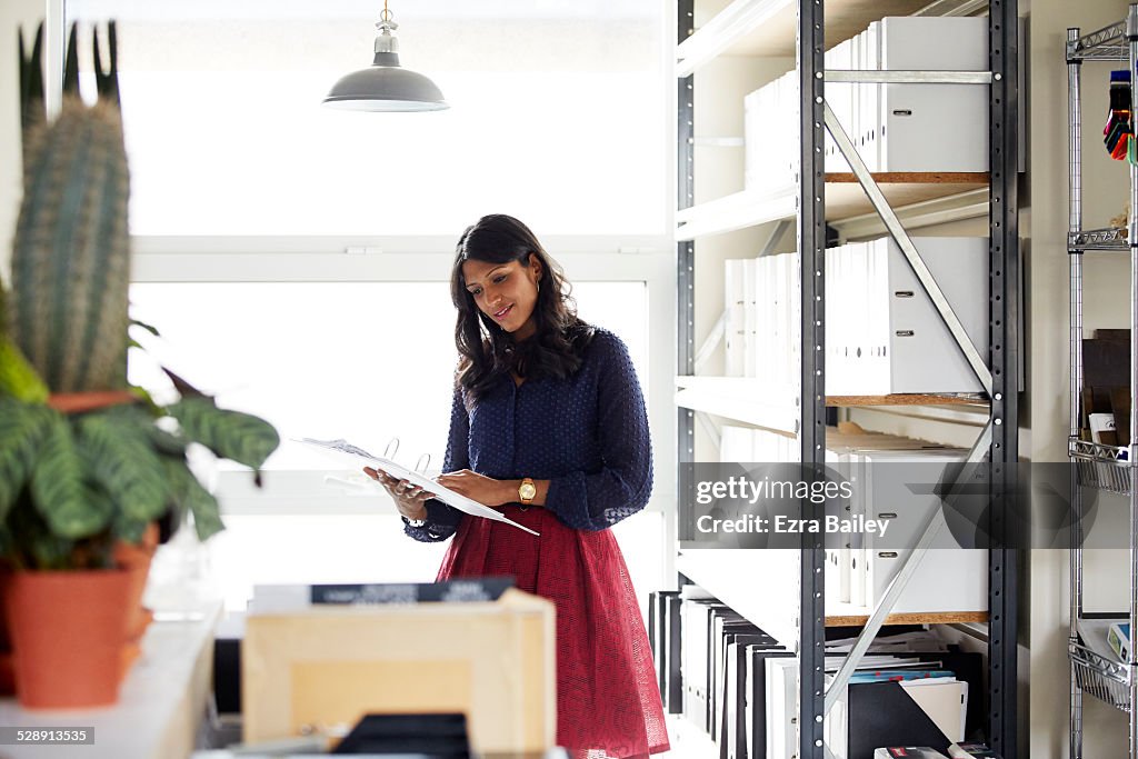 Female office worker reading a file by a window.