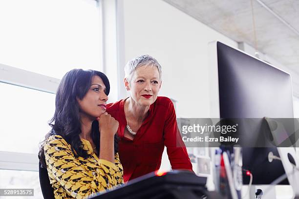 mature business woman mentoring younger employee. - coinvolgimento dei dipendenti foto e immagini stock