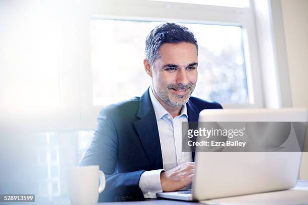 businessman working on a laptop smiling. - homme d'affaires photos et images de collection