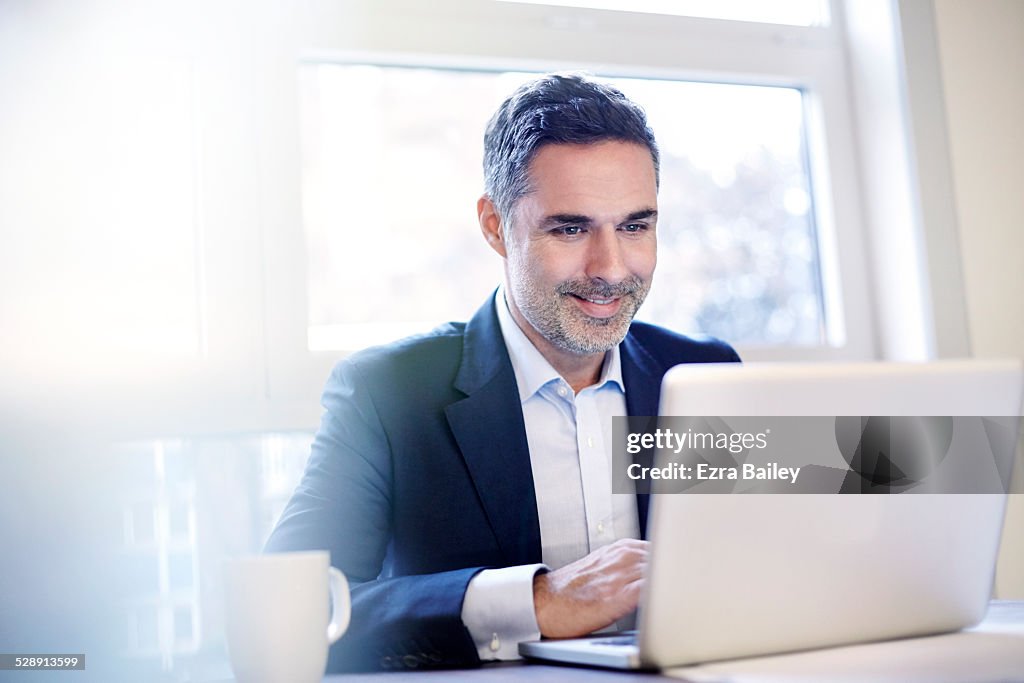 Businessman working on a laptop smiling.