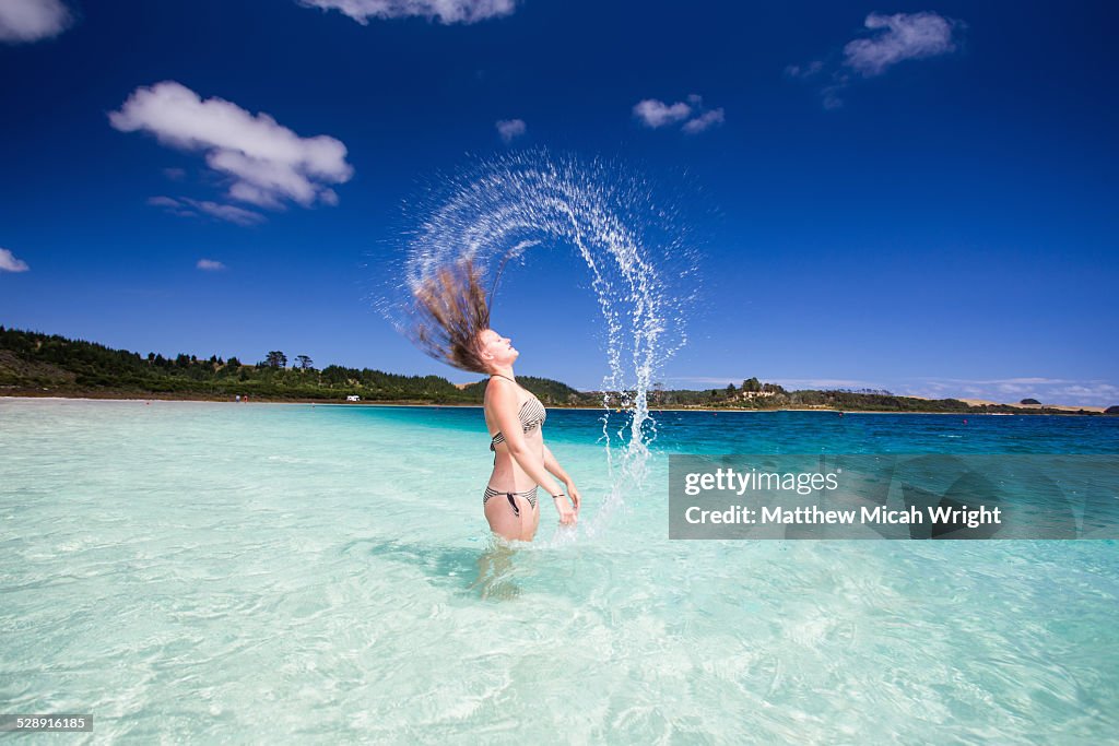 Girls whip their wet hair around in a lake