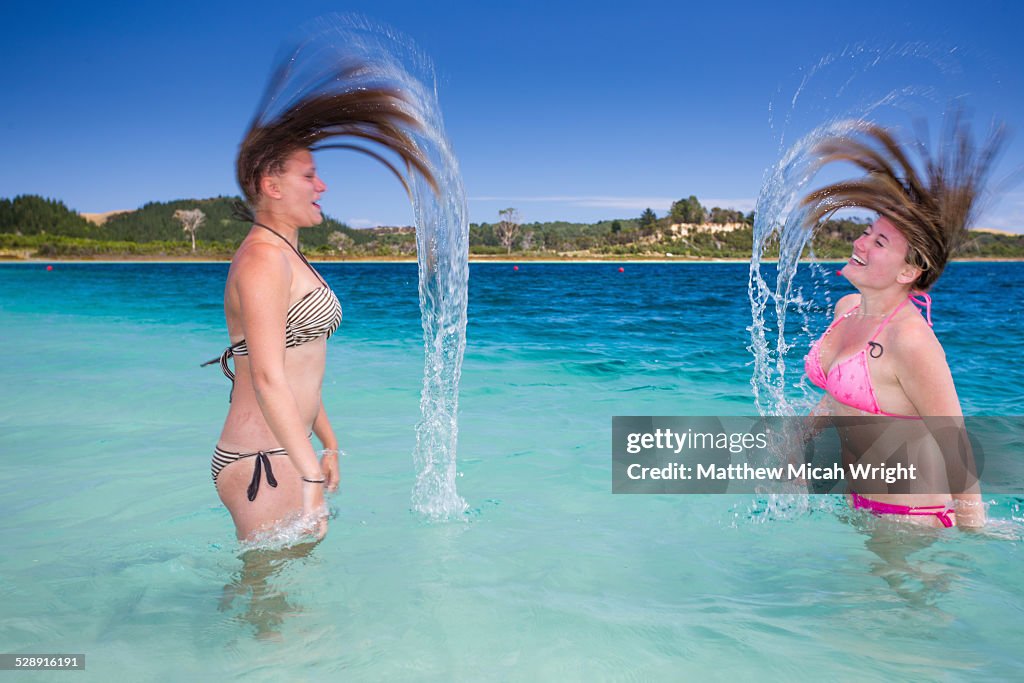 Girls whip their wet hair around in a lake