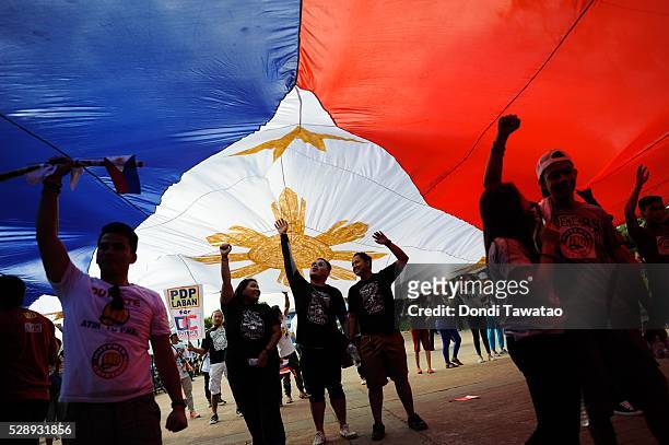Supporters of presidential frontrunner Rodrigo Duterte carry a Philippine flag during his final campaign rally on May 7, 2016 in Manila, Philippines....