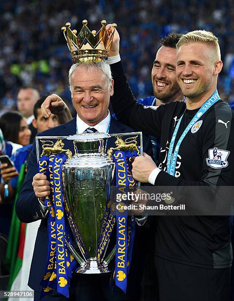 Claudio Ranieri poses with the Premier League Trophy while Kasper Schmeichel puts the crown on the head of the manager as players and staffs...