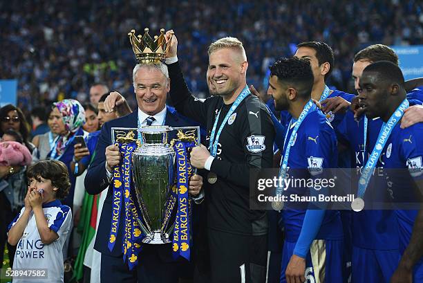 Claudio Ranieri poses with the Premier League Trophy while Kasper Schmeichel puts the crown on the head of the manager as players and staffs...