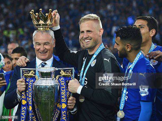 Claudio Ranieri poses with the Premier League Trophy while Kasper Schmeichel puts the crown on the head of the manager as players and staffs...