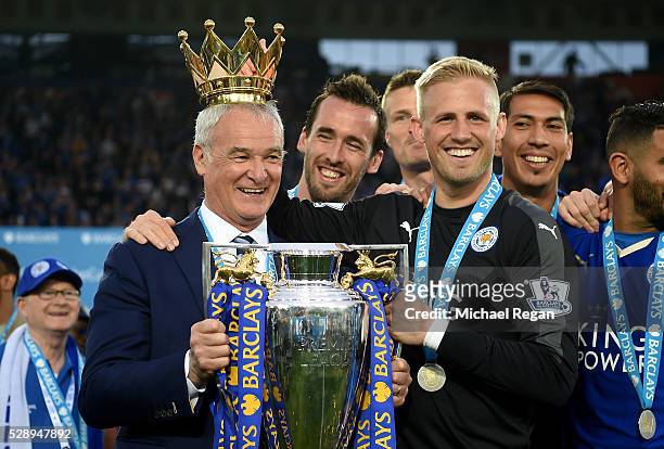 Claudio Ranieri poses with the Premier League Trophy while Kasper Schmeichel puts the crown on the head of the manager as players and staffs...