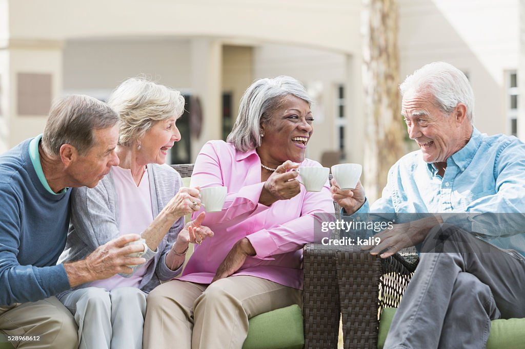 Multiracial senior friends outdoors drinking coffee