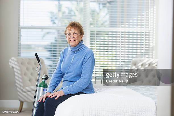 mujer mayor en su casa con tanque de oxígeno portátil - medical oxygen equipment fotografías e imágenes de stock