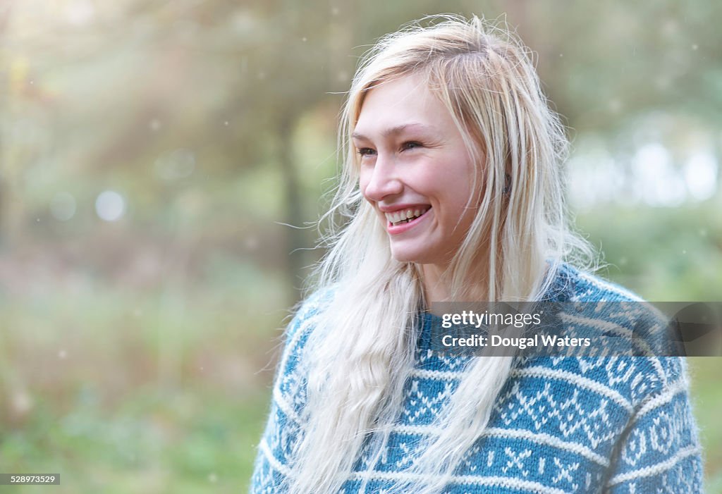 Woman smiling in countryside with falling snow.