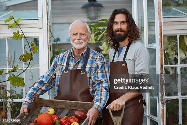 father & son in front of greenhouse with produce - father son business europe stock pictures, royalty-free photos & images