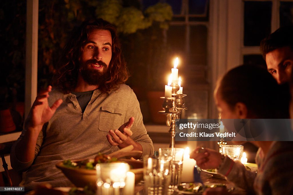 Man telling story at family dinner in gardenhouse