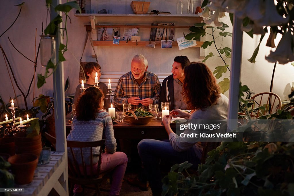 Three generations having cozy meal in garden house