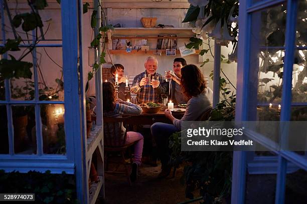 three generations having cozy meal in garden house - evening meal stock pictures, royalty-free photos & images