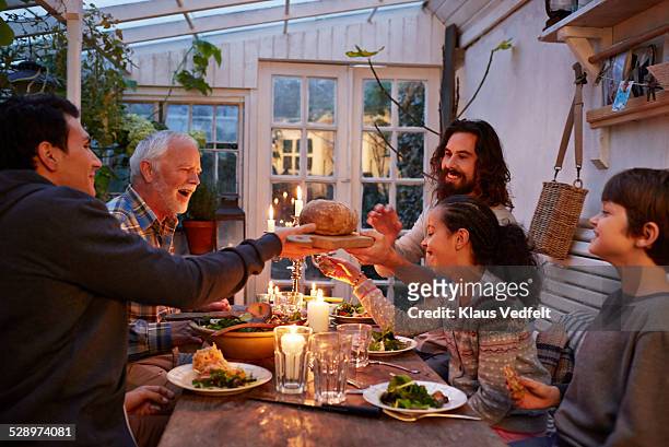 family having dinner in greenhouse, passing bread - man offering bread stock pictures, royalty-free photos & images