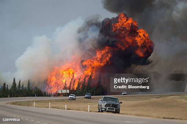 Wildfire burns behind abandoned vehicles on the Alberta Highway 63 near Fort McMurray, Alberta, Canada, on Saturday, May 7, 2016. Wildfires ravaging...