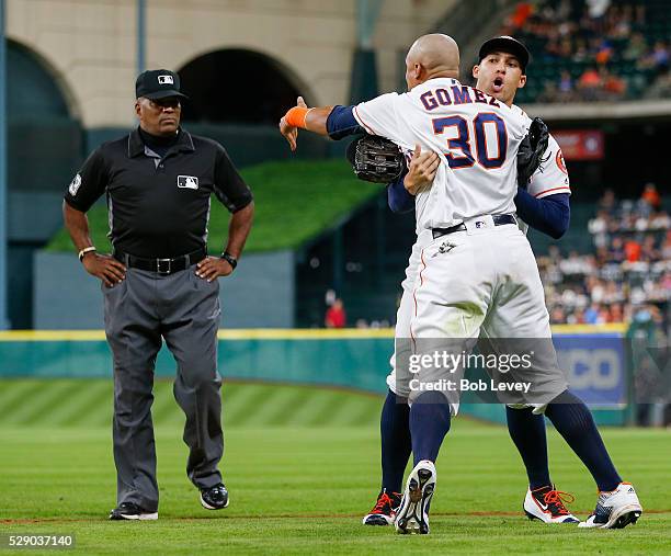 Carlos Gomez of the Houston Astros is held back by George Springer as he argues with umpire Laz Diaz as he took the field to start the 10th inning on...