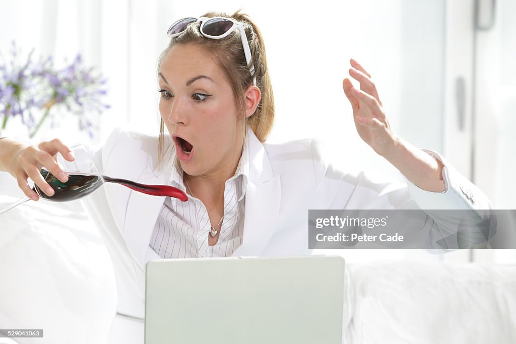 Woman dressed in white spilling glass of wine .