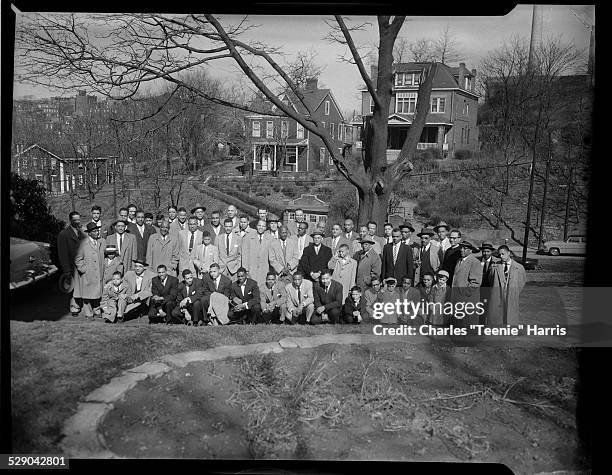 Group portrait of Alpha Phi Alpha fraternity members and boys, including Reverend LeRoy Patrick and Robert Goode on right, outside with houses on...