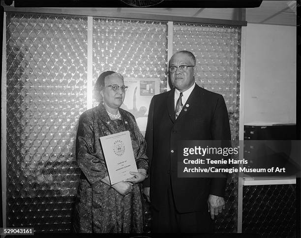 Woman holding pamphlet inscribed 'NAACP founded 1909 Campaign Kit for Membership Chairmen,' and man, posed in front of glass divider, Pittsburgh,...