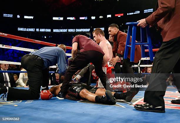 Canelo Alvarez kneels over Amir Khan as officials tend to Khan after Alvarez delivered a knockout punch during the sixth round of their WBC...