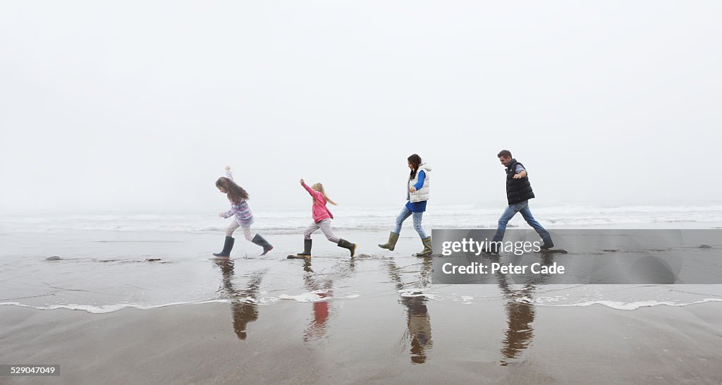 Family on beach balancing on stepping stones .