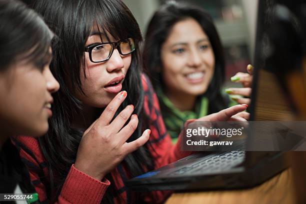teenage asian girls of different ethnicity using laptop together. - indian girl pointing stock pictures, royalty-free photos & images