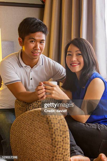 young asian couple with a hot drink - asian couple having hi tea stockfoto's en -beelden