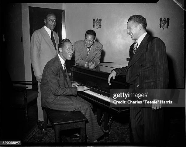 Four men, including George Thompson on left, and Warren Watson on right leaning against piano, in Loendi Club, Pittsburgh, Pennsylvania, circa...