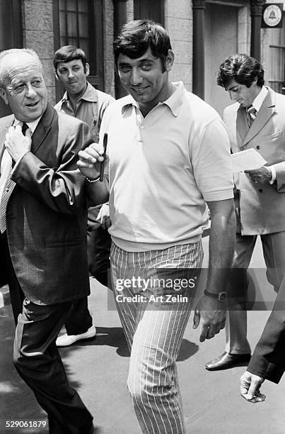 Joe Namath walking with a group of men on the street.; circa 1970; New York.