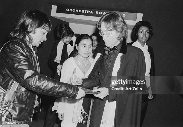 John Lennon giving autograph to hound who became photographer Vinny Zafonti; circa 1960; New York. Behind them is Japanese artist and musician Yoko...