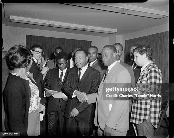 Dr. Martin Luther King Jr. Shaking hands with James McCoy Jr., with Mike Desmond on his right, surrounded by men and women, including Charles Harris...