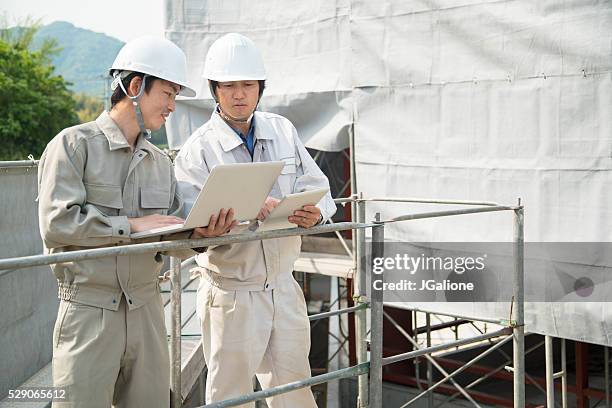 2 人の熟年構造について話す作業員とを見ている計画 - helmet ストックフォトと画像