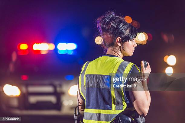 female police officer at night, talking on radio - verkeerspolitie stockfoto's en -beelden