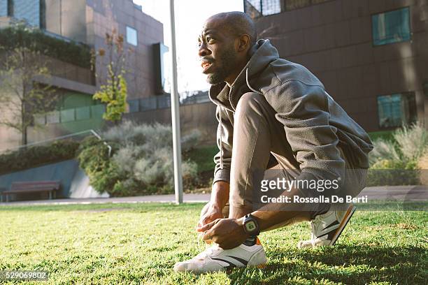 young man tying his shoelaces wearing sport clothes and smartwatch - tied up stock pictures, royalty-free photos & images