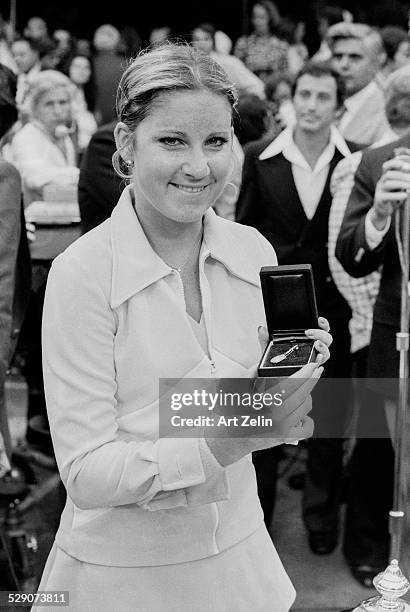 Chris Evert holding a tennis racquet pin after a tennis match; circa 1970; New York.