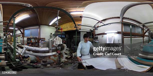 Press operator oversees kimono fabric being pressed flat after the painting and dyeing process where it is often creased, during a stage of its...