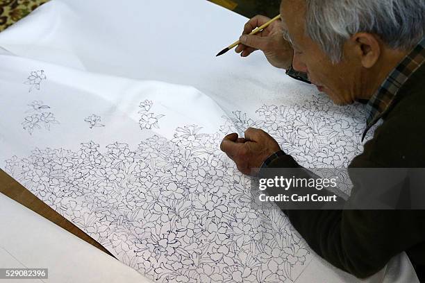 Drawing master Kenji Suhara draws the outline of designs on kimono fabric during a stage of its production process at the Sensyo Ichikawa kimono...