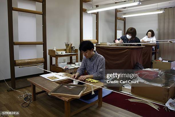 Drawing masters Ryugo Yamamoto, Junko Seki and Takako Yoshida paint designs on kimono fabric during a stage of its production process at the Sensyo...