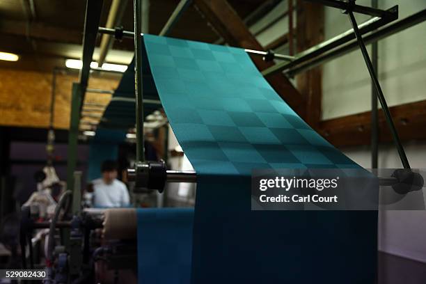 Press operator oversees kimono fabric being pressed flat after the painting and dyeing process where it is often creased, during a stage of its...